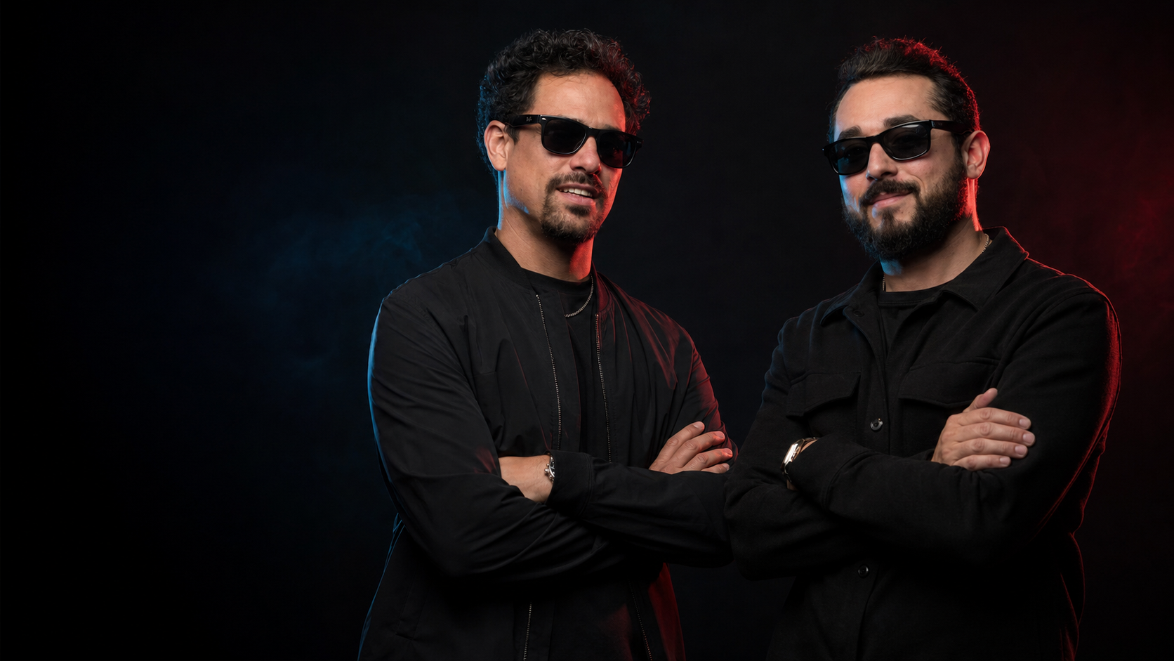 Comedy Calendar hosts Art Roche (left) and Sebastian Alvarez (right), arms folded under red and blue stage light